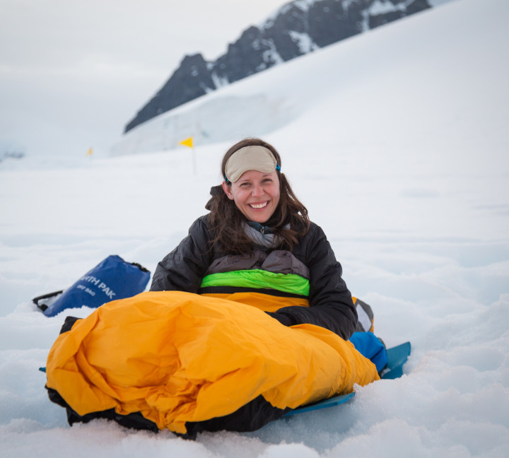 One of our guests smiles for a photo in theie bivvy bag as they wake up after overnight camping in Antarctica.