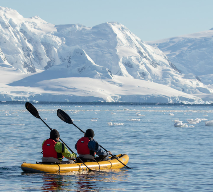 Two guests in dry suits paddle through Antarctic waters onboard our sit-on-top inflatable kayaks.