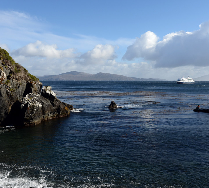 Zodiac boats pass by a rock formation at Cape Horn.