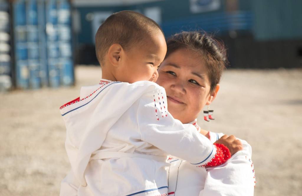 A woman in white holds her baby.