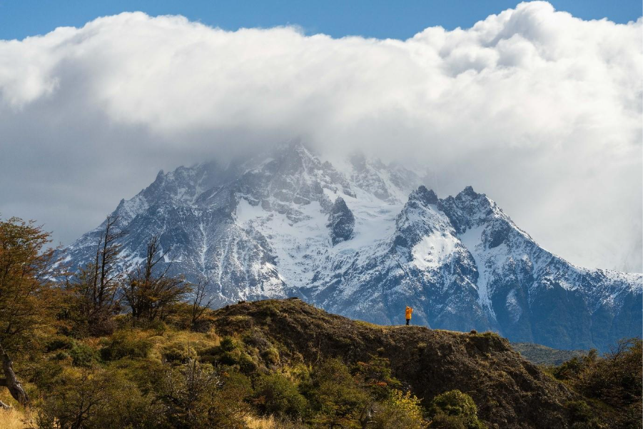 Photo of a guest between green landscape & icy mountains of Patagonia. 